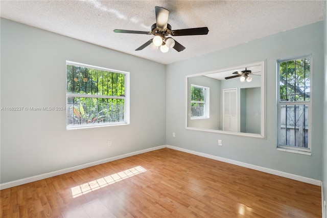 empty room with a textured ceiling, hardwood / wood-style flooring, and a healthy amount of sunlight