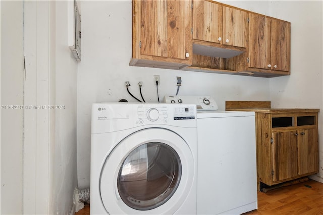 laundry room with cabinets, light wood-type flooring, and washing machine and clothes dryer