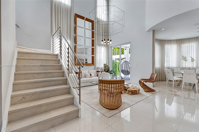 stairs featuring tile patterned floors, a high ceiling, and a notable chandelier