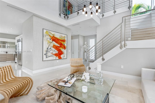 interior space with a notable chandelier, light tile patterned floors, and a high ceiling