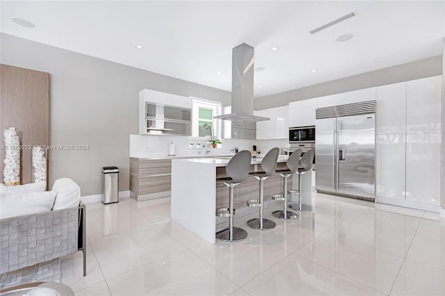 kitchen with built in appliances, island exhaust hood, a center island, and white cabinets