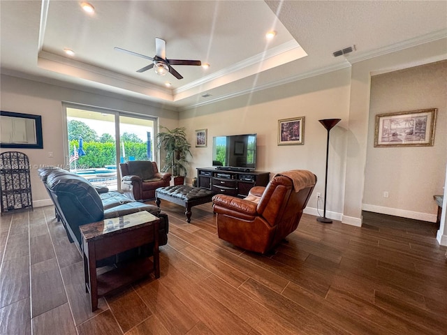 living room featuring ornamental molding, dark hardwood / wood-style floors, and a tray ceiling