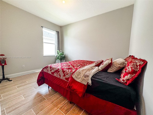 bedroom with a textured ceiling and wood-type flooring