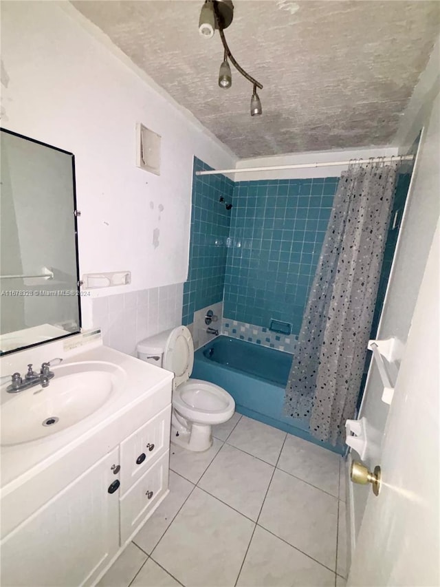 full bathroom featuring a textured ceiling, shower / bath combination with curtain, toilet, tile patterned floors, and vanity