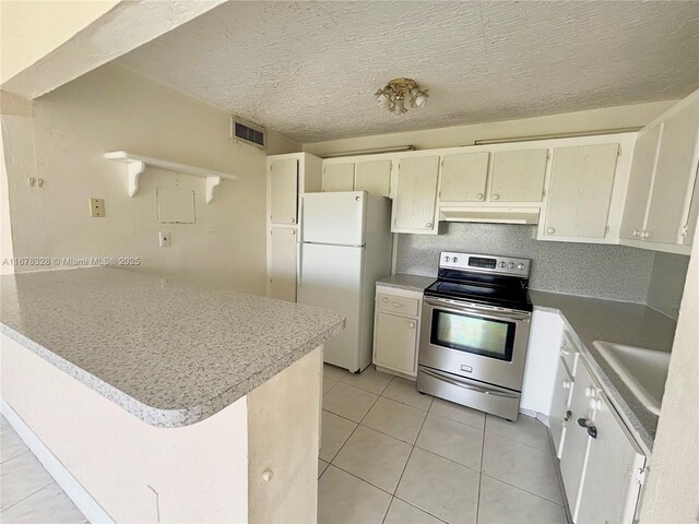 kitchen with light tile patterned flooring, sink, a textured ceiling, electric range, and white fridge