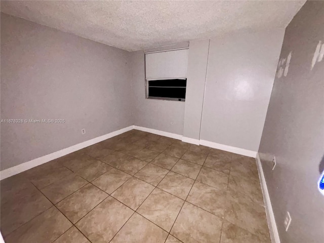 empty room with tile patterned flooring and a textured ceiling