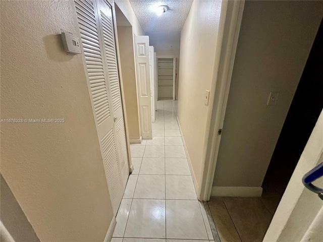 corridor with a textured ceiling and light tile patterned floors