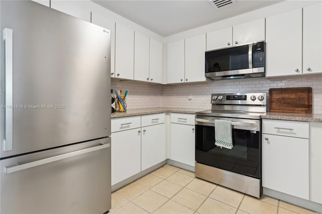 kitchen with light tile patterned floors, appliances with stainless steel finishes, white cabinets, and decorative backsplash