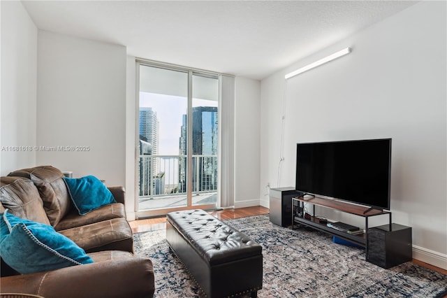 living room featuring expansive windows, baseboards, and wood finished floors