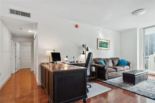 office space with dark wood-style flooring, visible vents, and baseboards