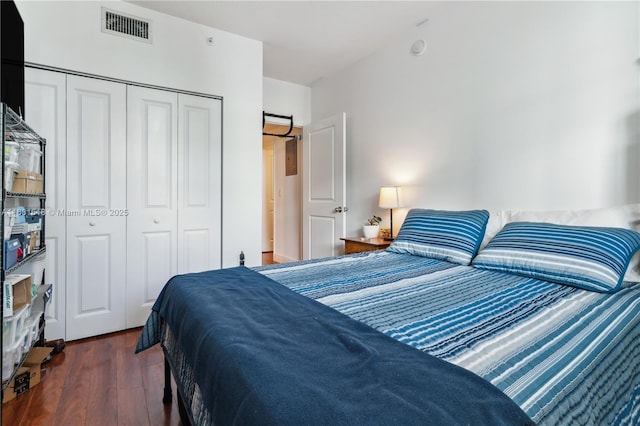 bedroom with a closet, visible vents, and dark wood finished floors