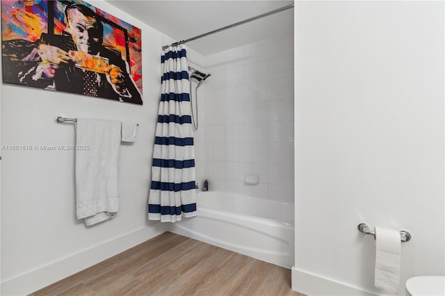 bathroom featuring shower / tub combo, wood finished floors, and baseboards