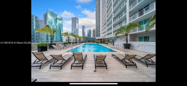 community pool with a view of city and a patio