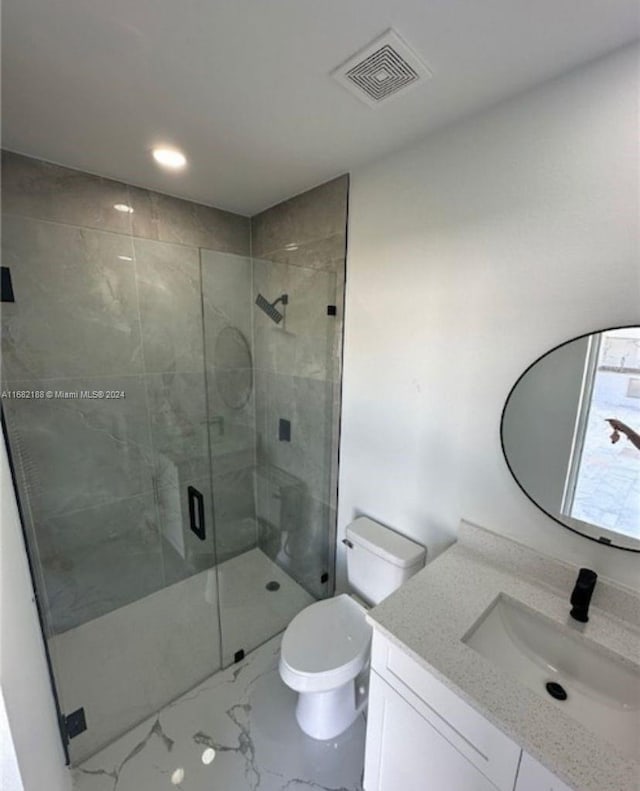 bathroom featuring toilet, a shower with shower door, and vanity