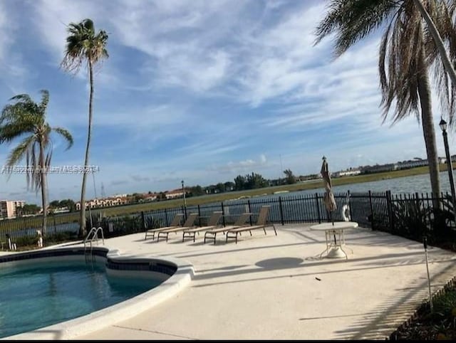 view of swimming pool with a patio area and a water view