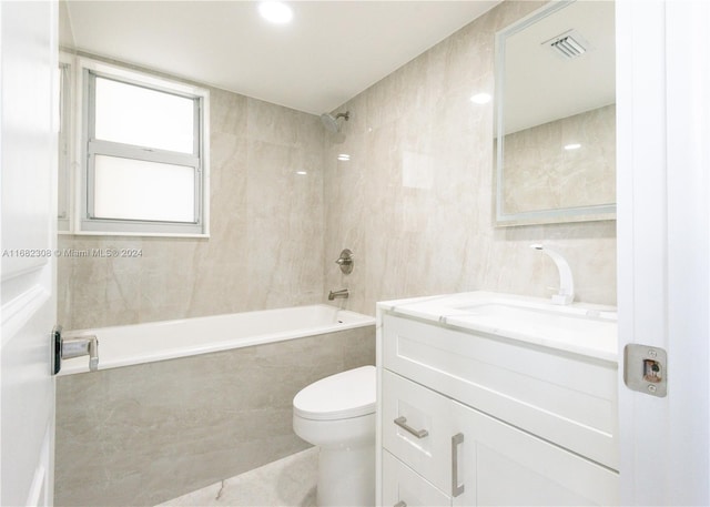 full bathroom with vanity, toilet, tiled shower / bath combo, and tile walls