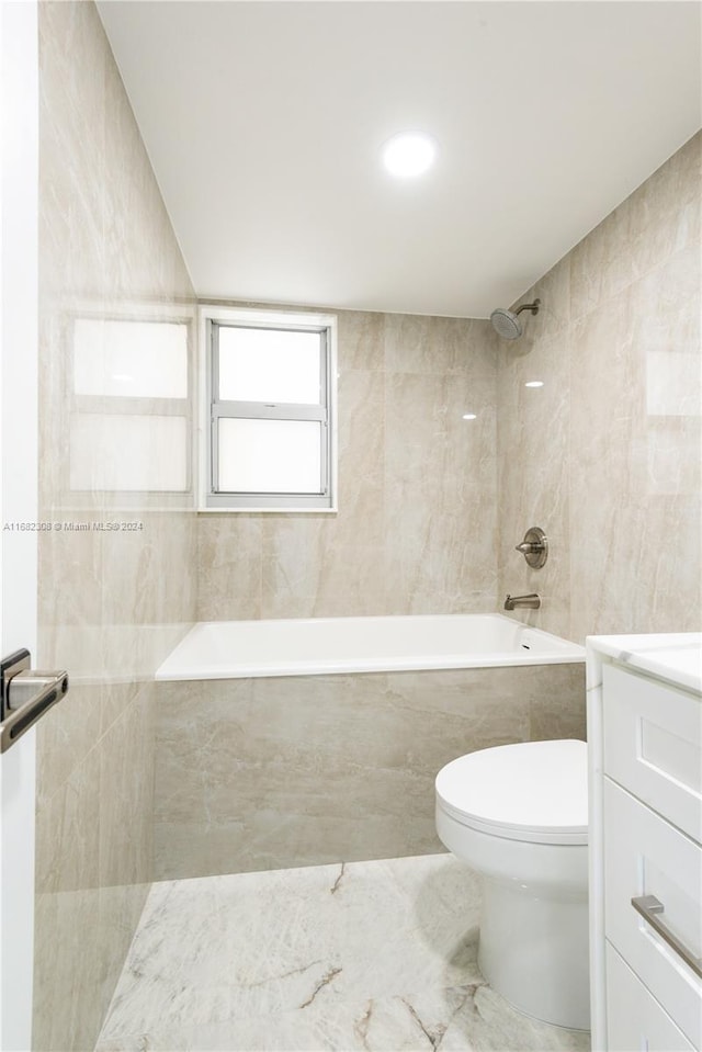 full bathroom featuring toilet, tiled shower / bath, vanity, and tile walls