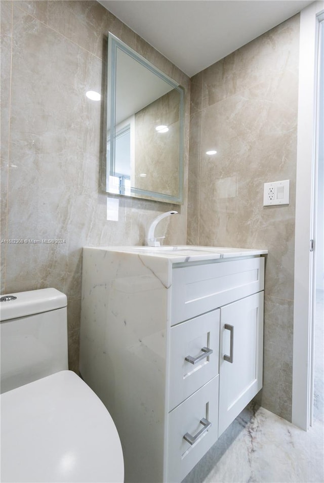 bathroom with vanity, toilet, and tile walls