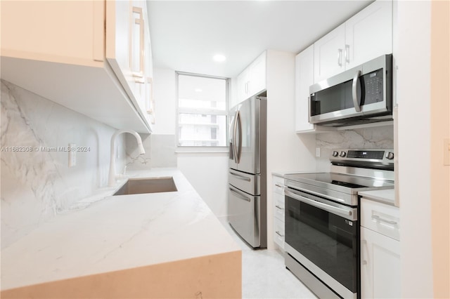 kitchen with decorative backsplash, white cabinetry, stainless steel appliances, and sink