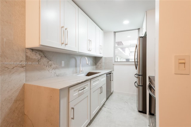 kitchen featuring decorative backsplash, stainless steel appliances, sink, white cabinets, and light stone counters