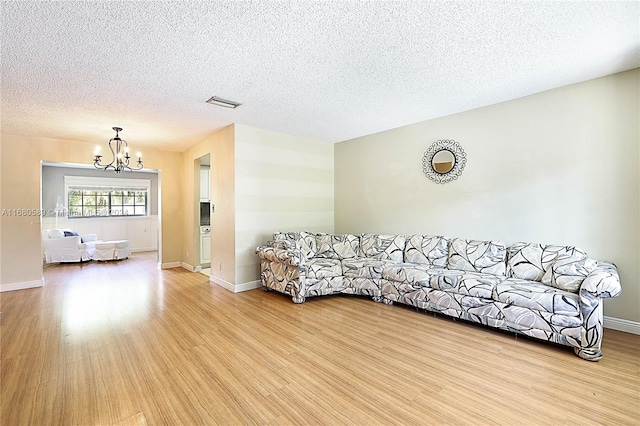 unfurnished living room featuring light hardwood / wood-style floors, an inviting chandelier, and a textured ceiling