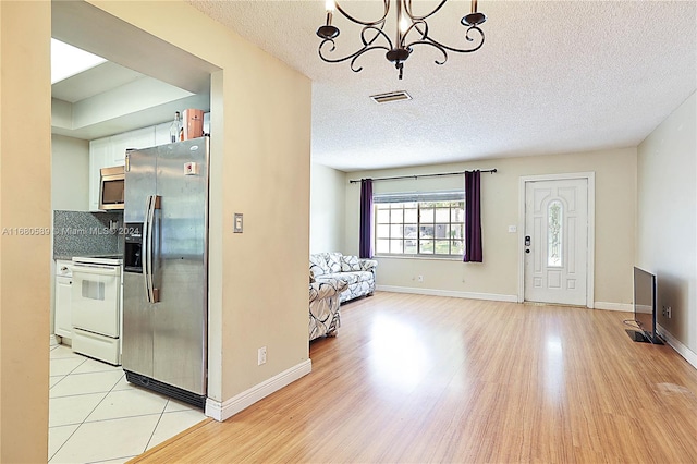 foyer entrance with a chandelier, a textured ceiling, and light hardwood / wood-style floors