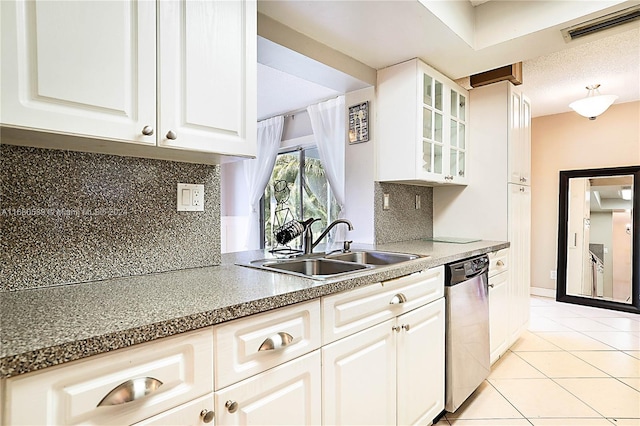 kitchen featuring white cabinets, tasteful backsplash, light tile patterned floors, stainless steel dishwasher, and sink