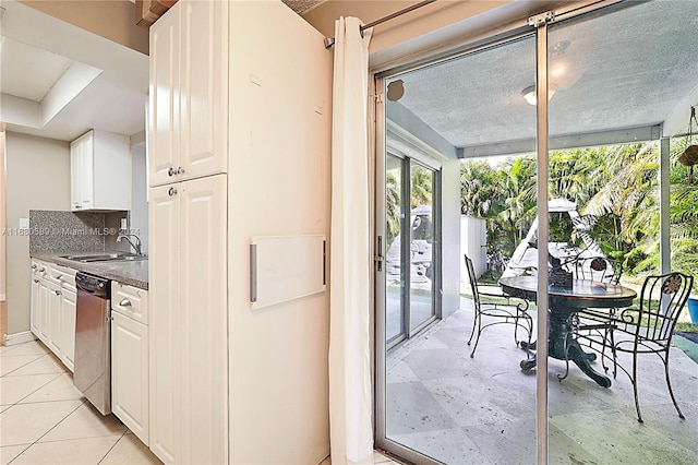 kitchen featuring tasteful backsplash, sink, a textured ceiling, white cabinetry, and stainless steel dishwasher