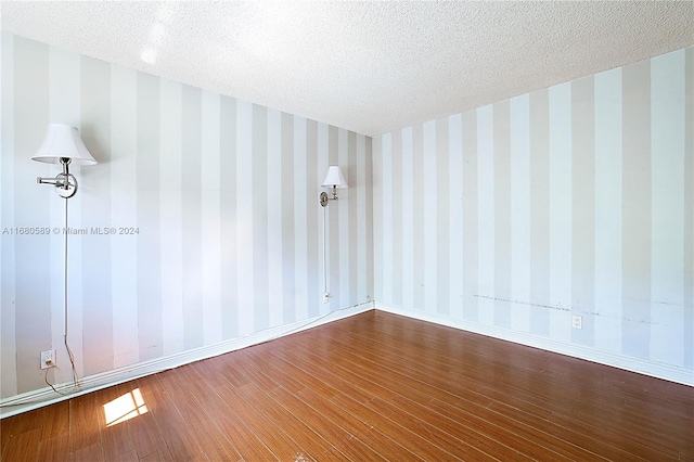 empty room featuring a textured ceiling and wood-type flooring