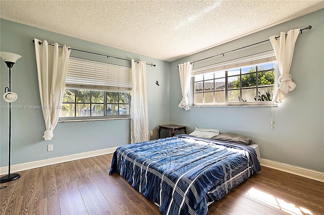 bedroom featuring hardwood / wood-style flooring, a textured ceiling, and multiple windows