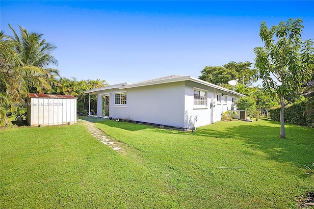 exterior space featuring a storage unit, a yard, and central AC unit