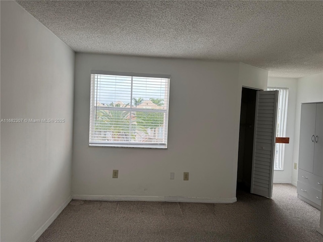 empty room with carpet floors and a textured ceiling