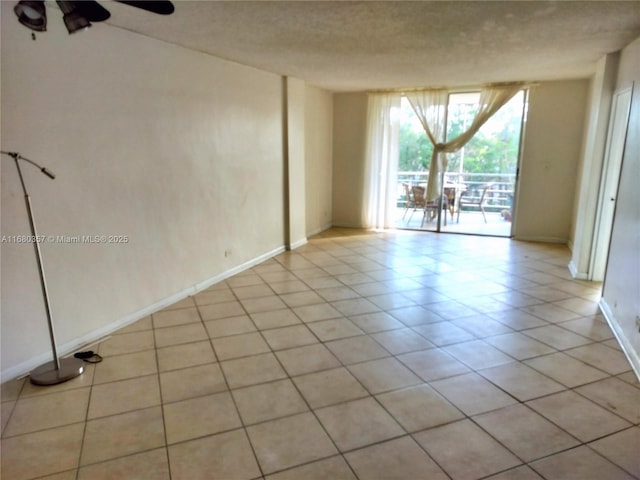 empty room with ceiling fan and light tile patterned floors