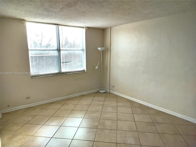 unfurnished room featuring a textured ceiling and light tile patterned flooring