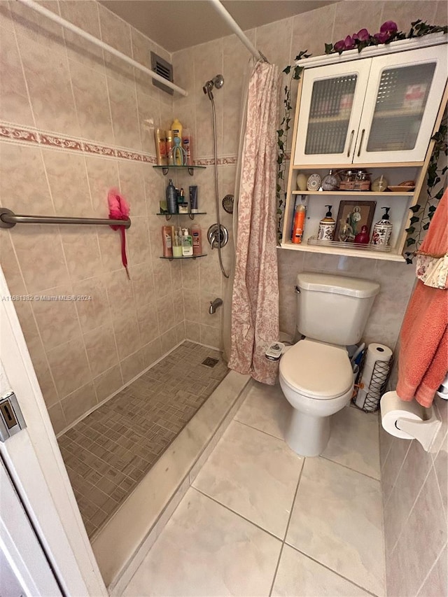 bathroom featuring tile patterned floors, a shower with curtain, tile walls, and toilet