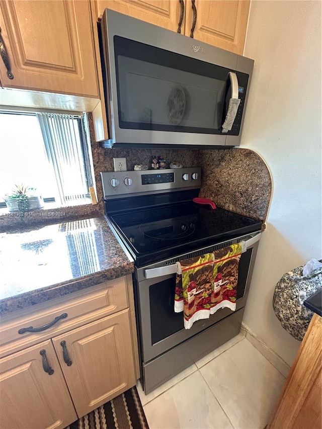 kitchen with decorative backsplash, light tile patterned floors, appliances with stainless steel finishes, and dark stone counters