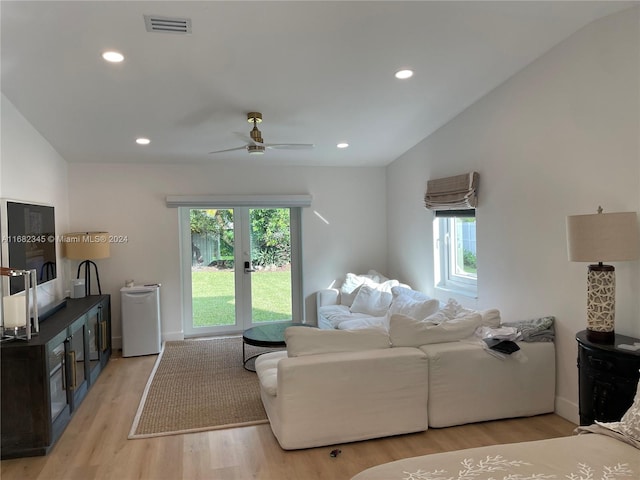 living room with light hardwood / wood-style flooring, lofted ceiling, and ceiling fan