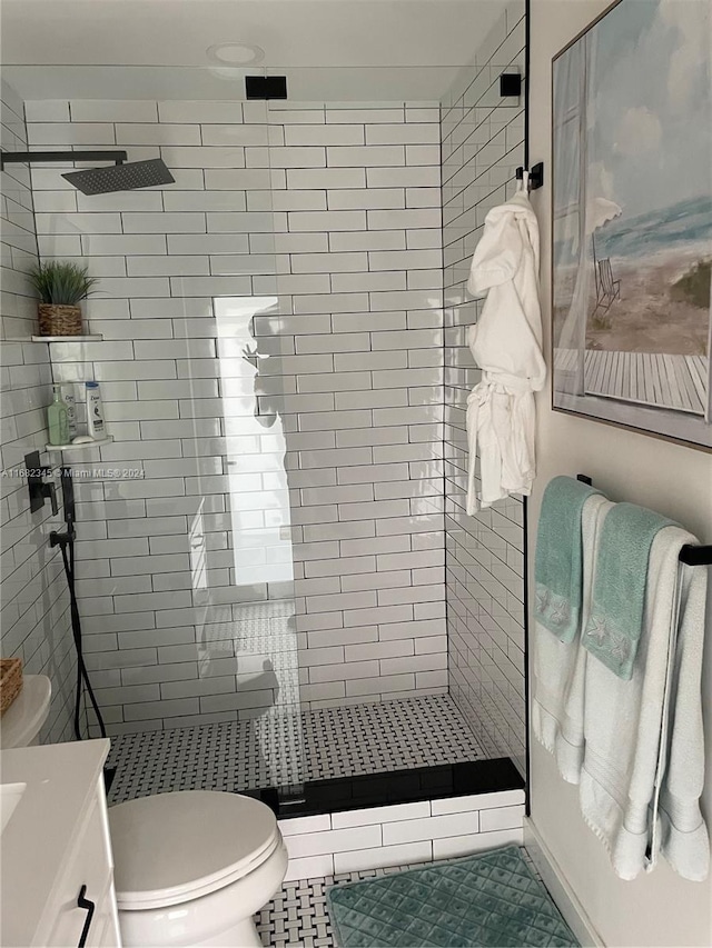 bathroom with vanity, toilet, a tile shower, and tile patterned flooring