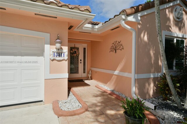 doorway to property featuring visible vents and stucco siding