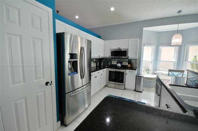 kitchen with white cabinets, stainless steel appliances, hanging light fixtures, and backsplash