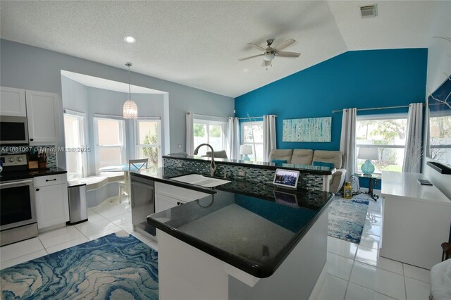 kitchen featuring a ceiling fan, a sink, dark countertops, appliances with stainless steel finishes, and light tile patterned floors