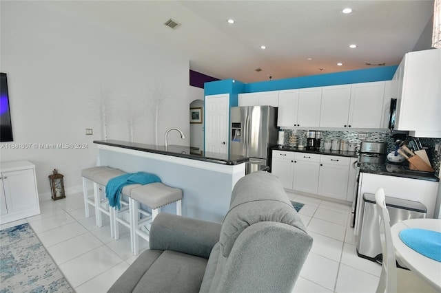 kitchen with tasteful backsplash, a kitchen breakfast bar, stainless steel appliances, white cabinets, and light tile patterned floors