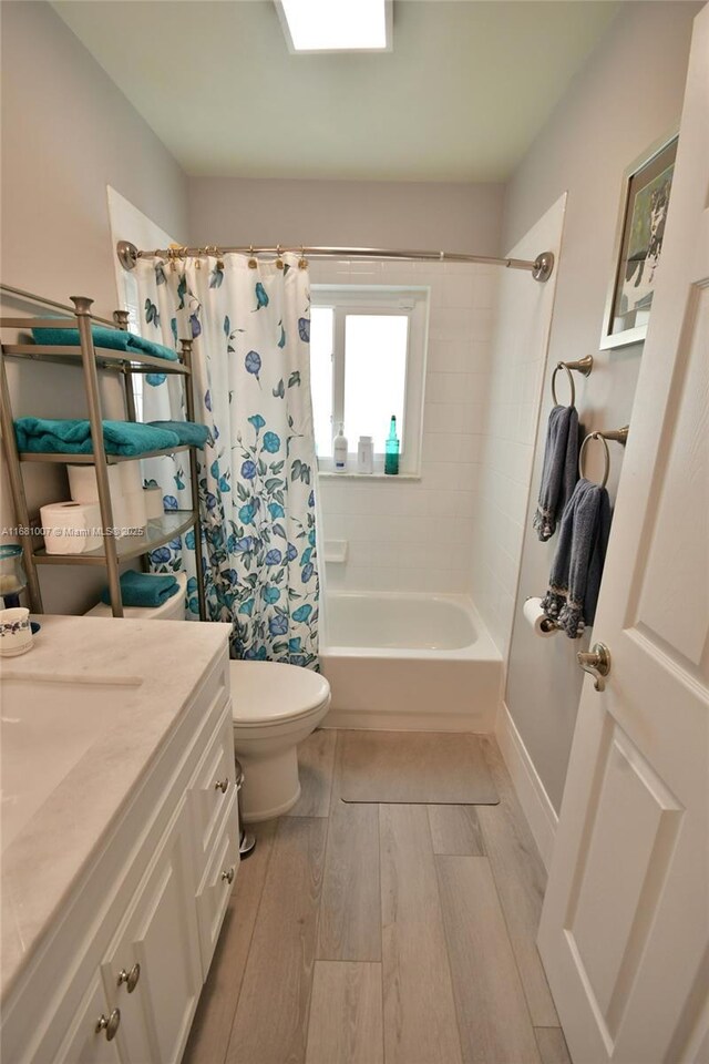 full bath featuring vanity, toilet, shower / tub combo, and wood finished floors
