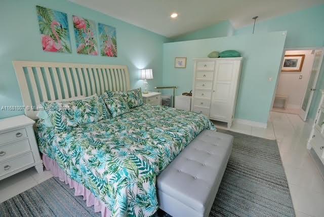 bedroom with vaulted ceiling, light tile patterned floors, and recessed lighting