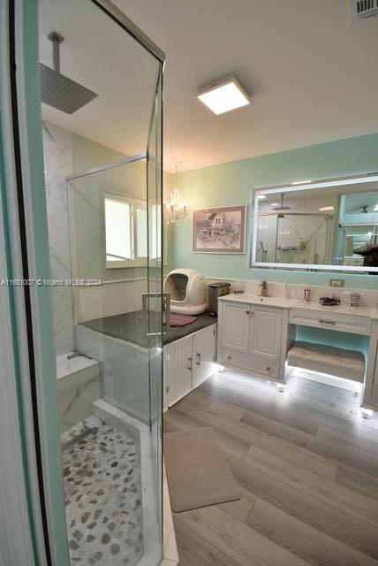 bathroom featuring vanity, a shower with shower door, a chandelier, and hardwood / wood-style floors