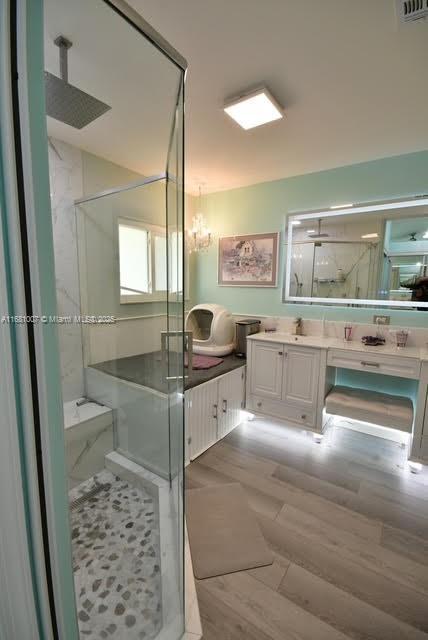 full bath with vanity, wood finished floors, visible vents, and a marble finish shower