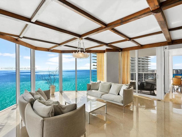 living room with coffered ceiling, a notable chandelier, expansive windows, and a water view