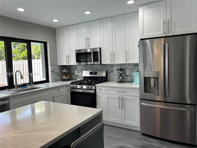 kitchen with appliances with stainless steel finishes, decorative backsplash, white cabinets, and sink