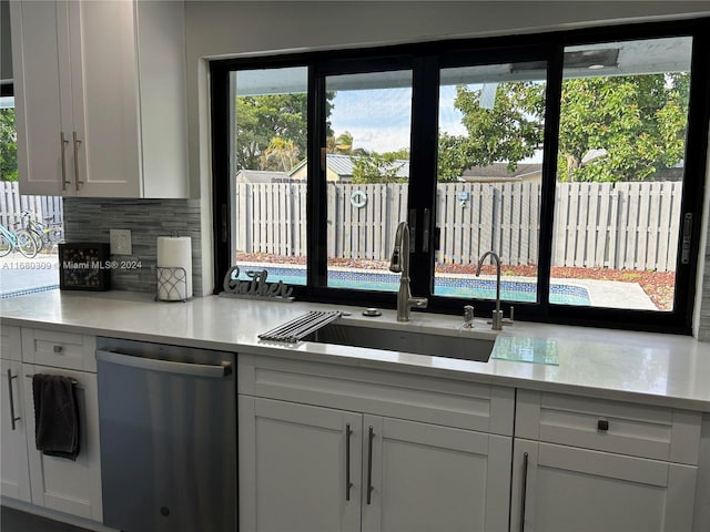 kitchen with stainless steel dishwasher, sink, white cabinets, and tasteful backsplash