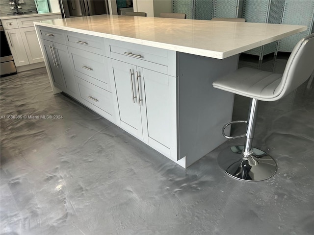 kitchen with decorative backsplash, white cabinets, a kitchen island, a kitchen breakfast bar, and light stone countertops